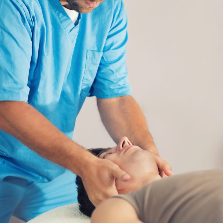 Physiotherapist doing healing treatment on man's neck, Therapist wearing blue uniform, Osteopath,  Chiropractic adjustment, patient lying on massage table